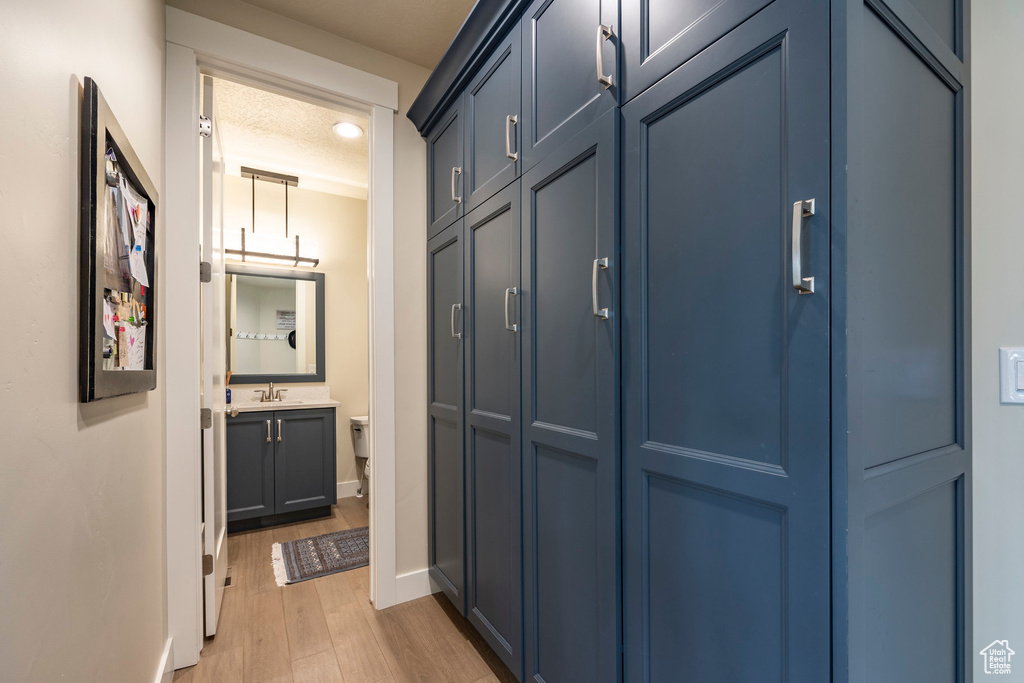 Corridor with sink, a textured ceiling, and light wood-type flooring