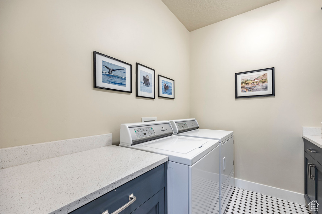 Laundry area featuring independent washer and dryer, a textured ceiling, and cabinets