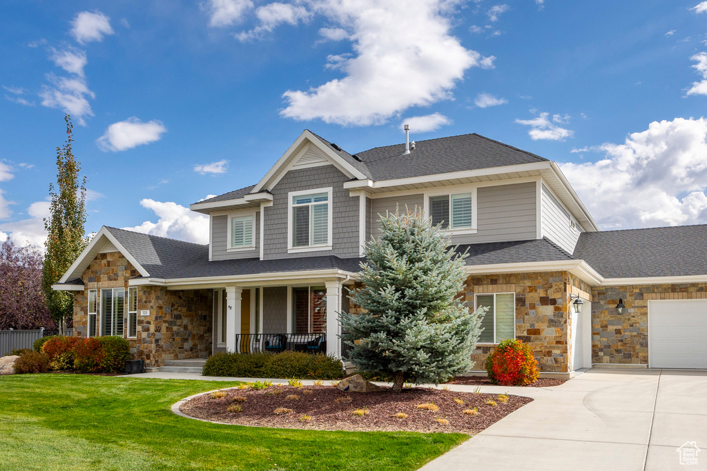 Craftsman-style home featuring covered porch, a front yard, and a garage