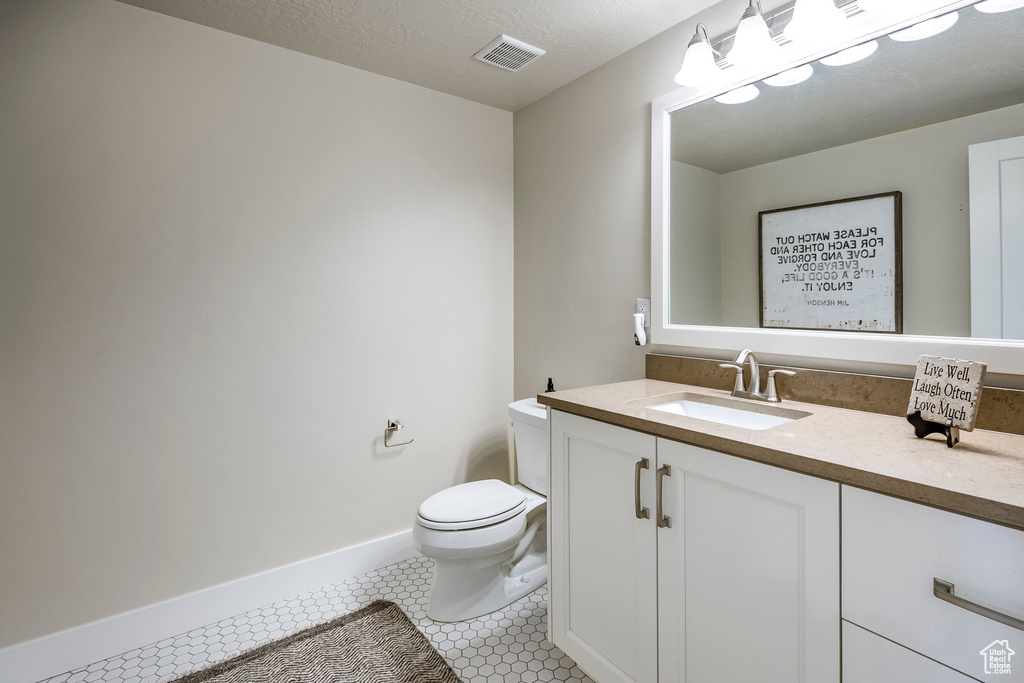 Bathroom featuring vanity, a textured ceiling, toilet, and tile patterned flooring