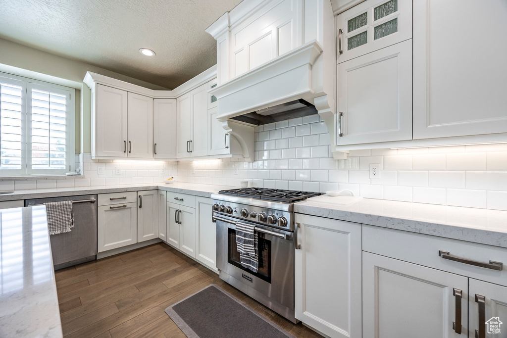 Kitchen featuring white cabinetry, stainless steel appliances, light stone countertops, and a textured ceiling