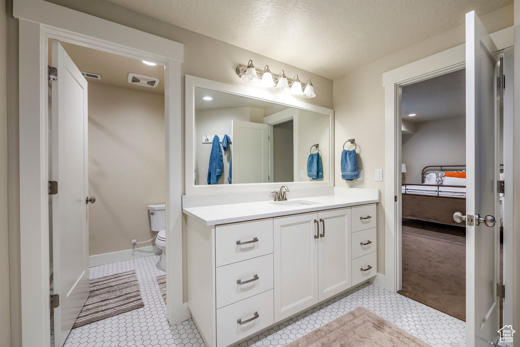 Bathroom with vanity, a textured ceiling, toilet, and tile patterned flooring