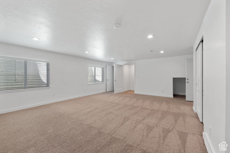 Empty room featuring a textured ceiling and light colored carpet