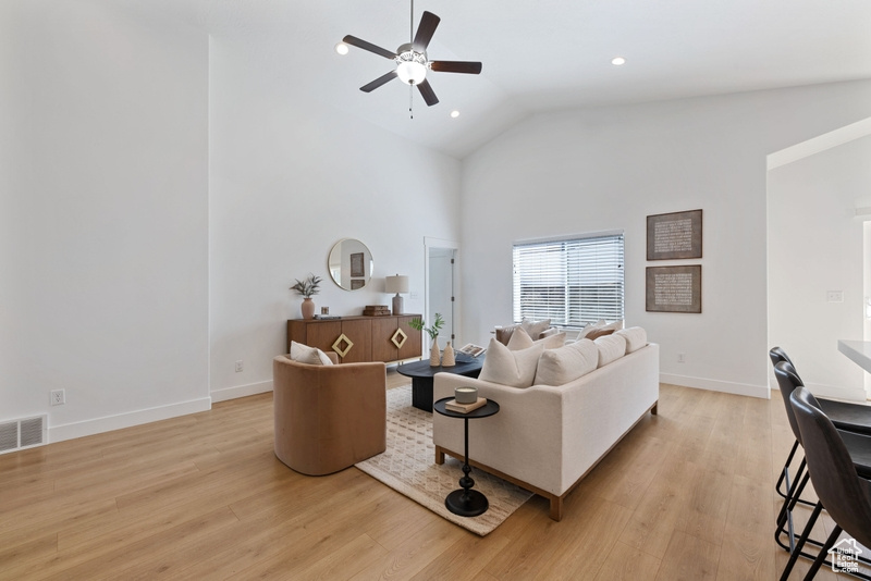 Living room with ceiling fan, light wood-type flooring, and high vaulted ceiling