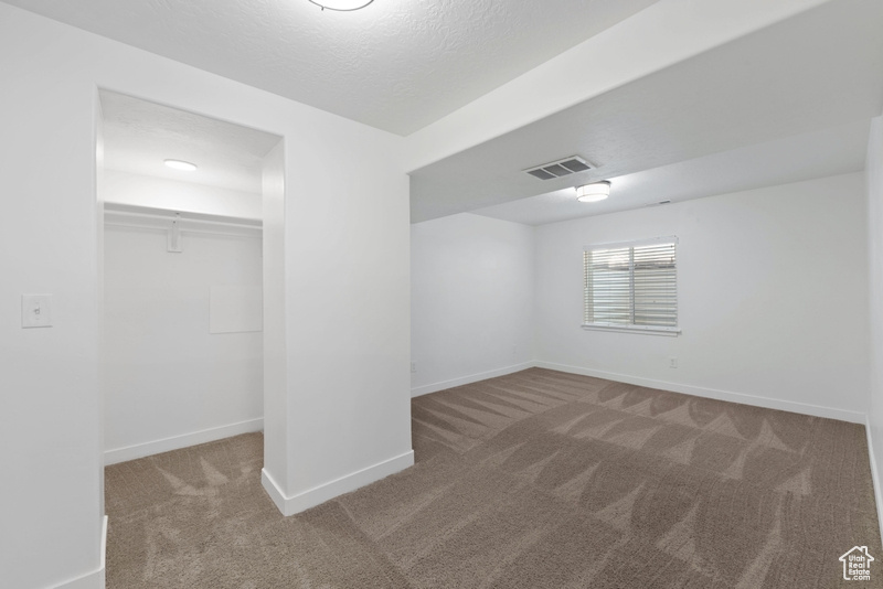 Interior space featuring light colored carpet and a textured ceiling