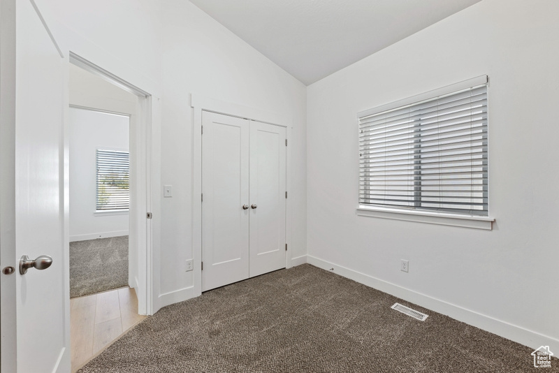 Unfurnished bedroom featuring carpet floors, lofted ceiling, and a closet