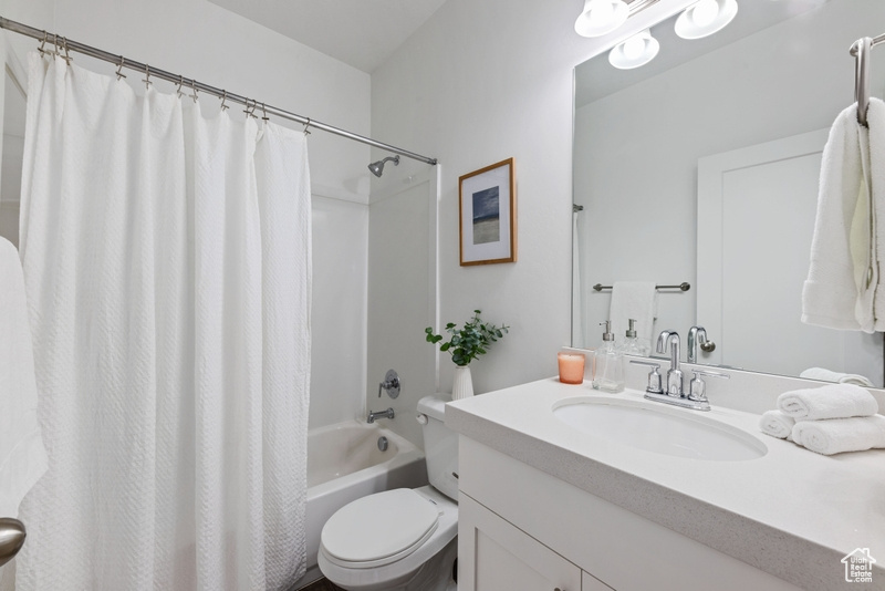 Full bathroom with vanity, toilet, and shower / bathtub combination with curtain