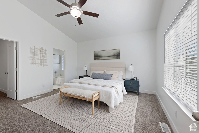 Carpeted bedroom with lofted ceiling, ceiling fan, and connected bathroom