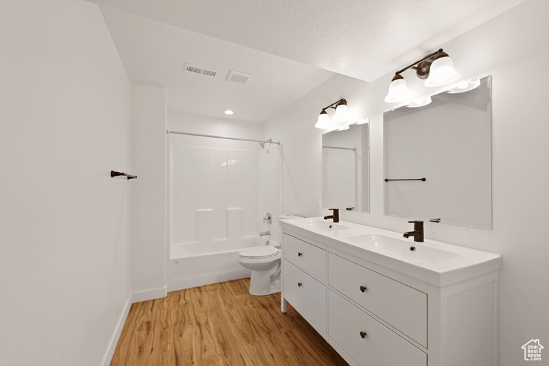 Full bathroom with shower / tub combination, hardwood / wood-style floors, vanity, and toilet