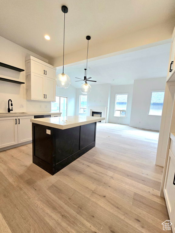 Kitchen with white cabinets, a healthy amount of sunlight, sink, and light wood-type flooring