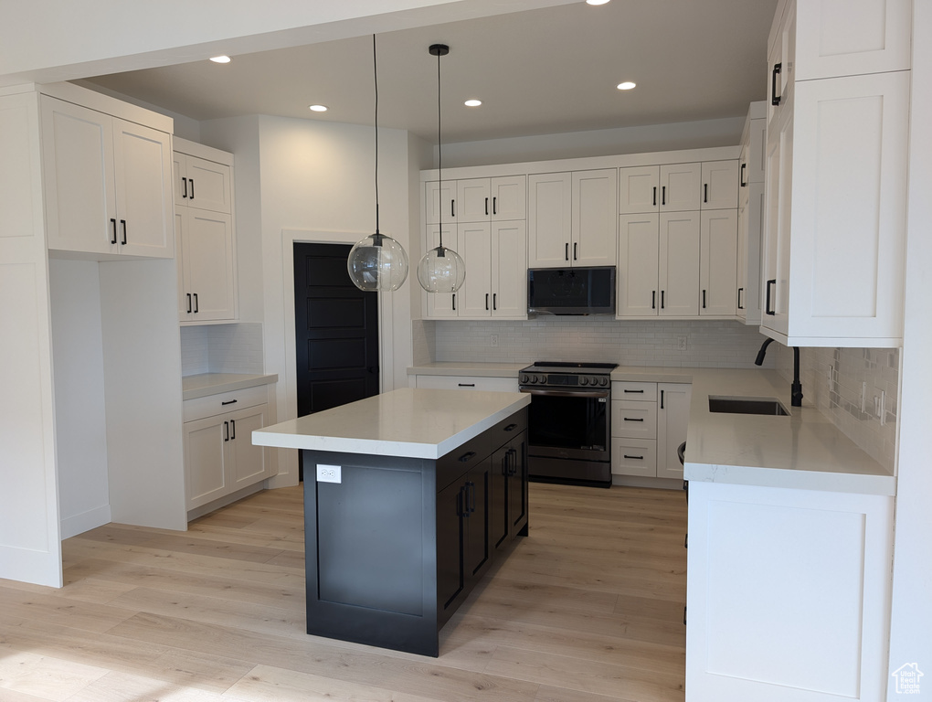 Kitchen featuring a center island, white cabinetry, black / electric stove, and sink