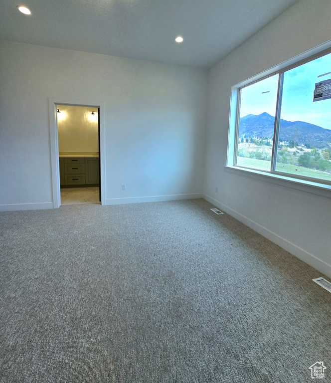 Empty room with a mountain view and light colored carpet