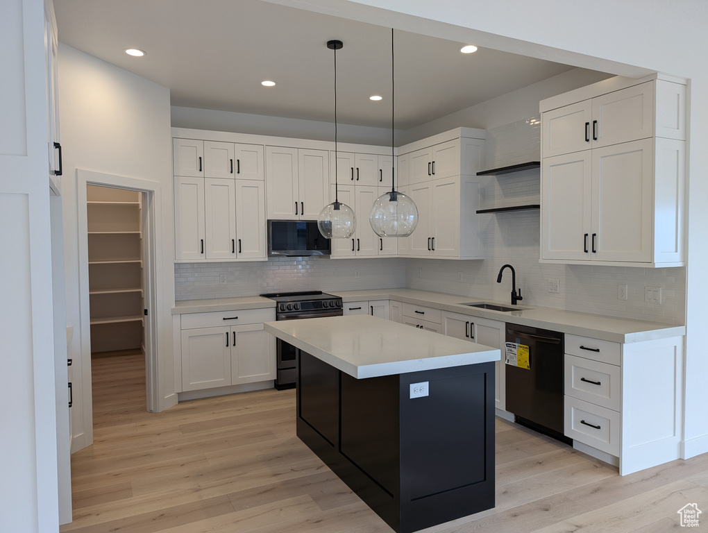 Kitchen with dishwasher, sink, range with electric stovetop, a kitchen island, and white cabinetry