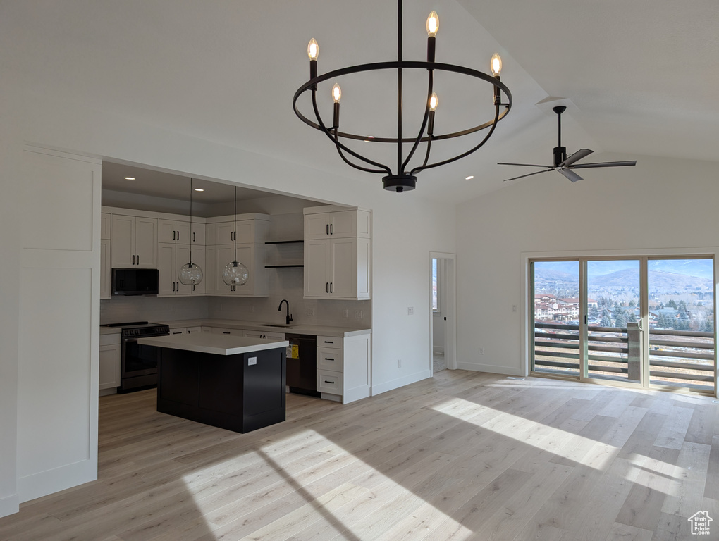 Kitchen featuring ceiling fan with notable chandelier, black appliances, decorative light fixtures, white cabinets, and a center island