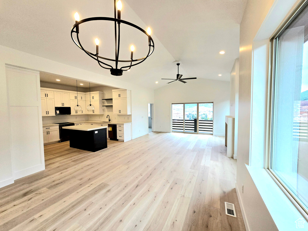Unfurnished living room with ceiling fan with notable chandelier, light hardwood / wood-style flooring, lofted ceiling, and sink