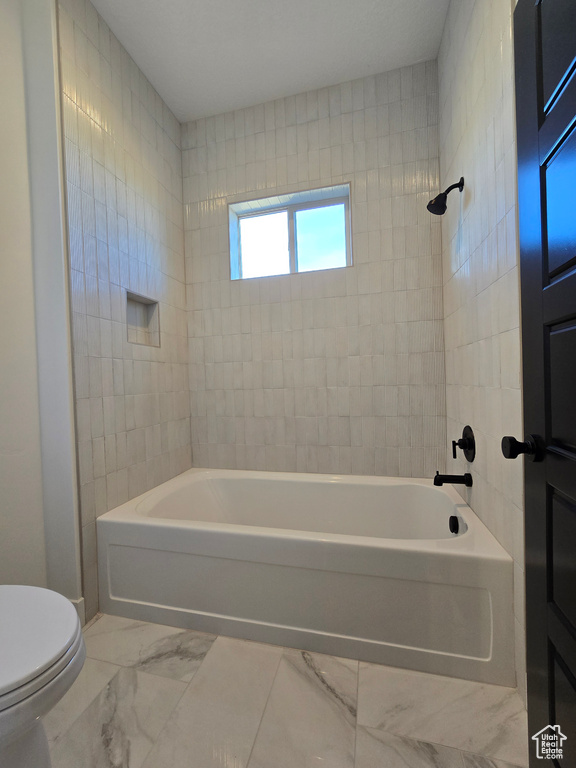 Bathroom featuring tiled shower / bath combo and toilet