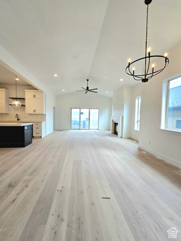 Unfurnished living room with lofted ceiling, light hardwood / wood-style flooring, and a healthy amount of sunlight