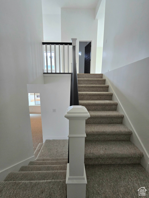 Stairway with carpet floors and a towering ceiling