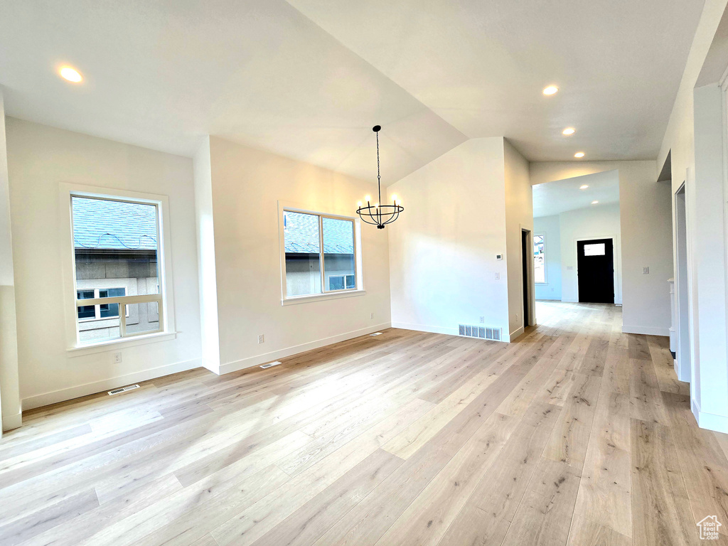 Interior space featuring an inviting chandelier, light hardwood / wood-style floors, vaulted ceiling, and a wealth of natural light