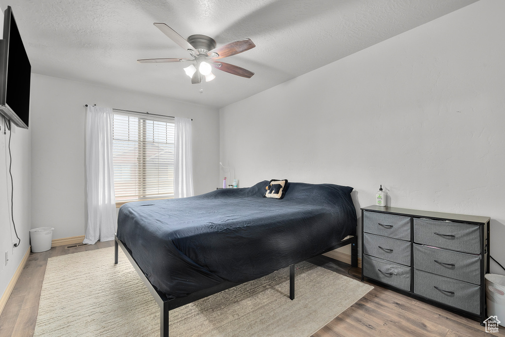 Bedroom featuring a textured ceiling, wood-type flooring, and ceiling fan