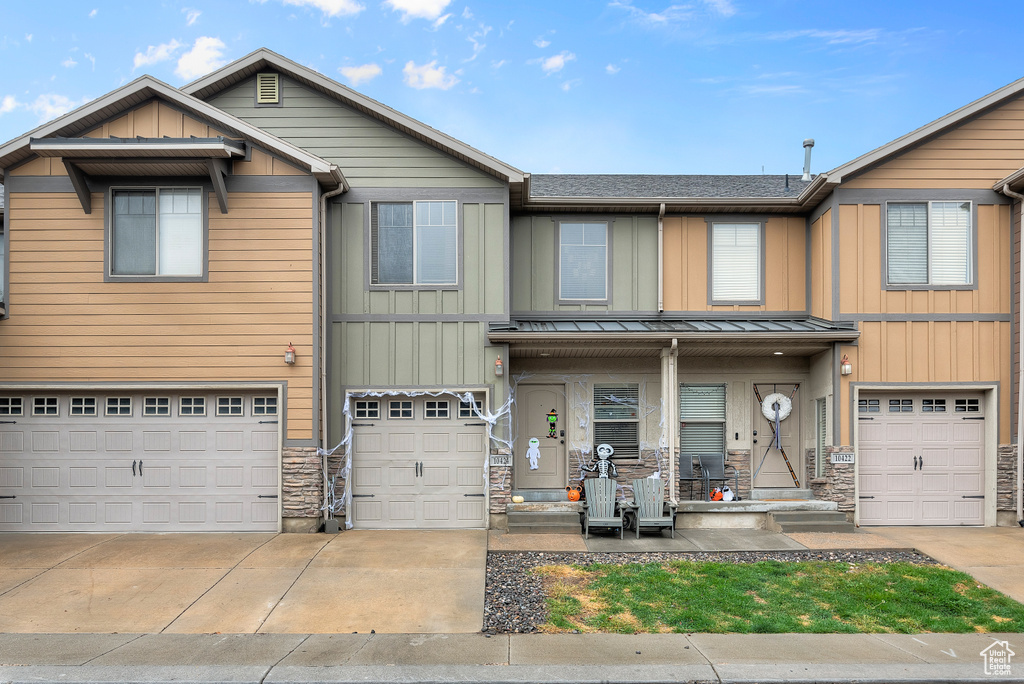 Townhome / multi-family property featuring covered porch and a garage