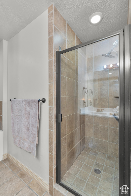 Bathroom with tile patterned floors, plus walk in shower, and a textured ceiling