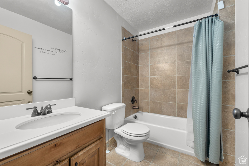 Full bathroom featuring tile patterned floors, shower / bath combo, toilet, vanity, and a textured ceiling