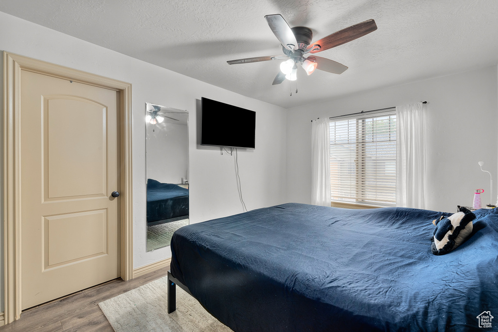 Bedroom featuring ceiling fan, a textured ceiling, and light hardwood / wood-style flooring