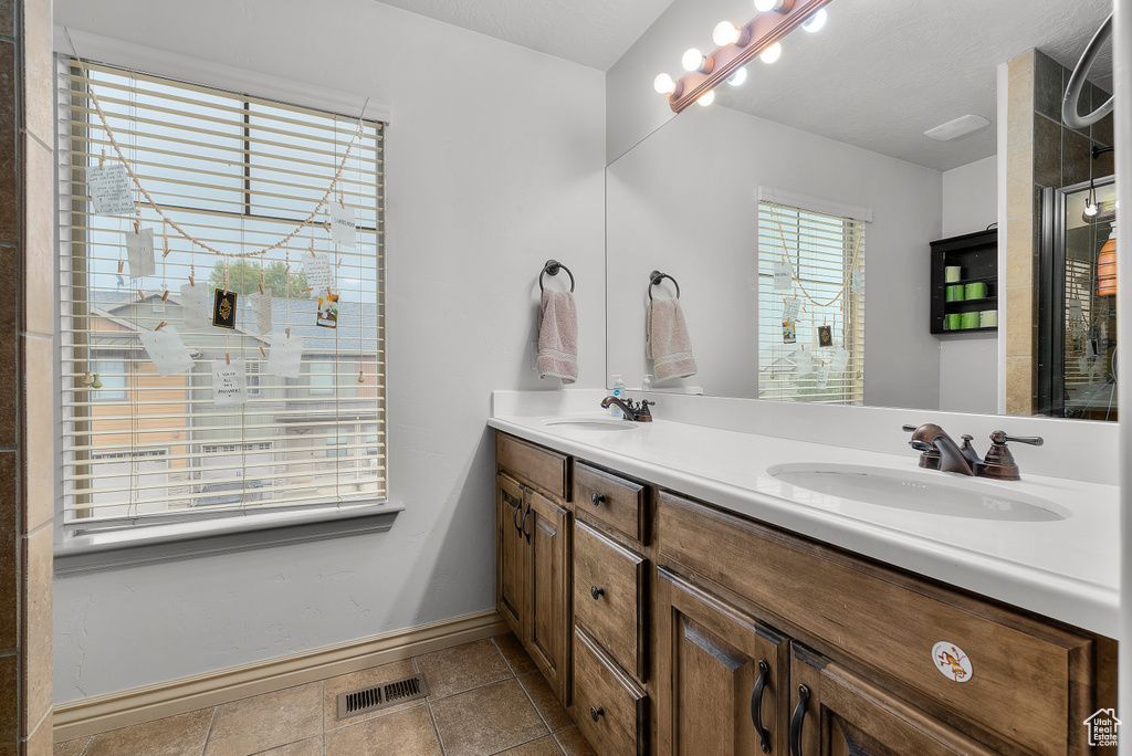 Bathroom with vanity, a shower, a healthy amount of sunlight, and tile patterned flooring