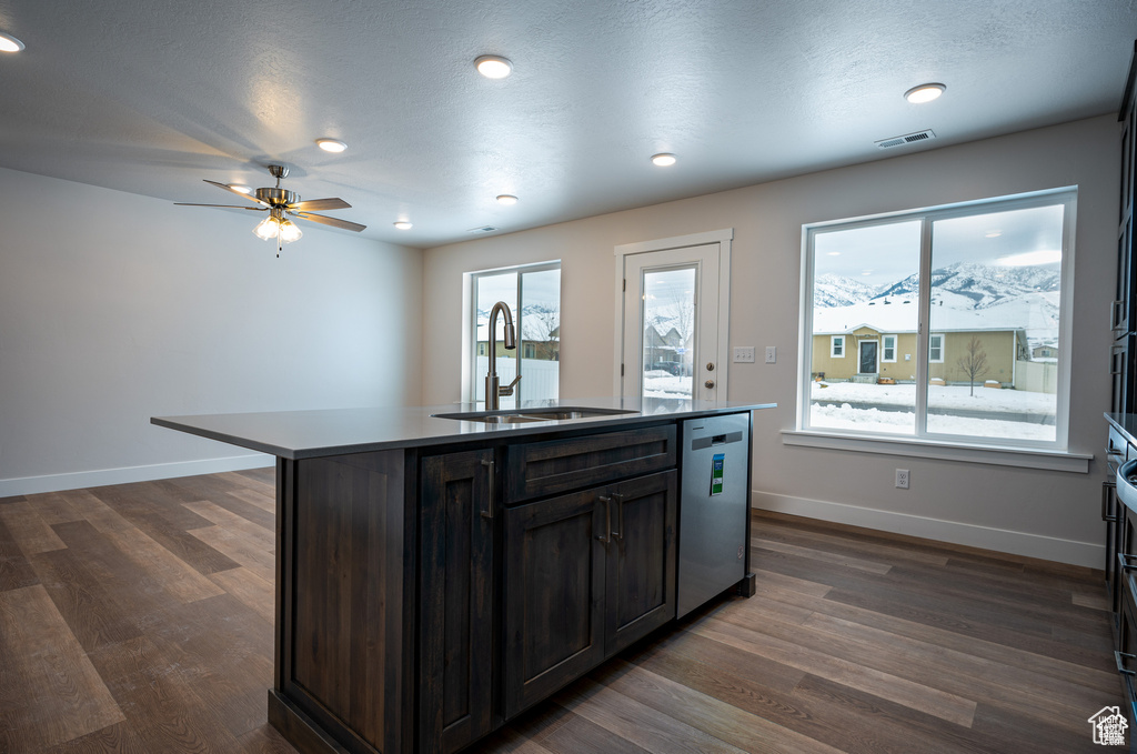 Kitchen with stainless steel dishwasher, dark hardwood / wood-style floors, sink, and a center island with sink