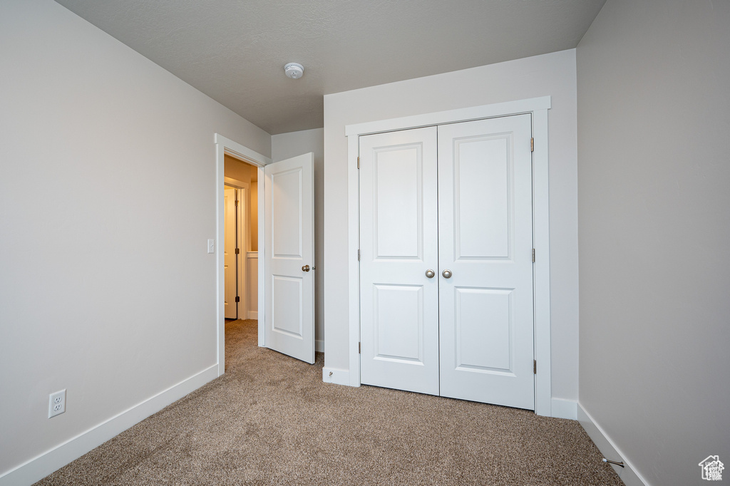 Unfurnished bedroom with light carpet and a closet