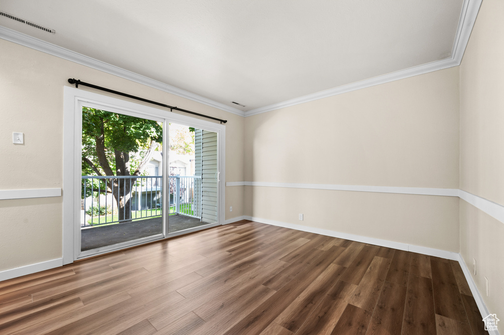 Spare room featuring crown molding and wood-type flooring