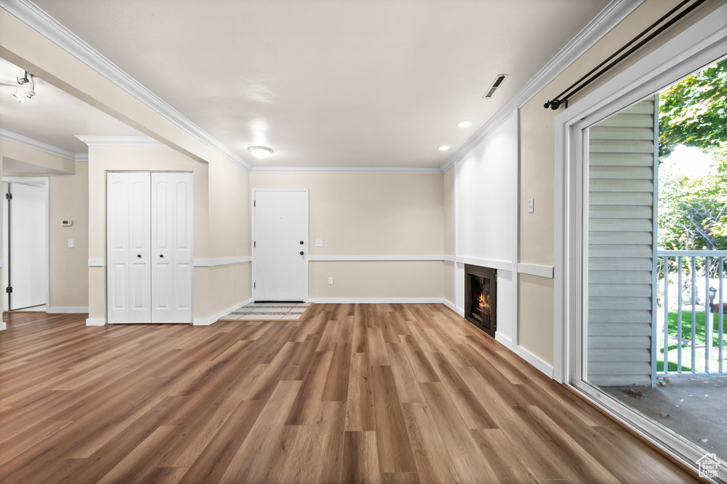 Unfurnished living room with crown molding and hardwood / wood-style flooring