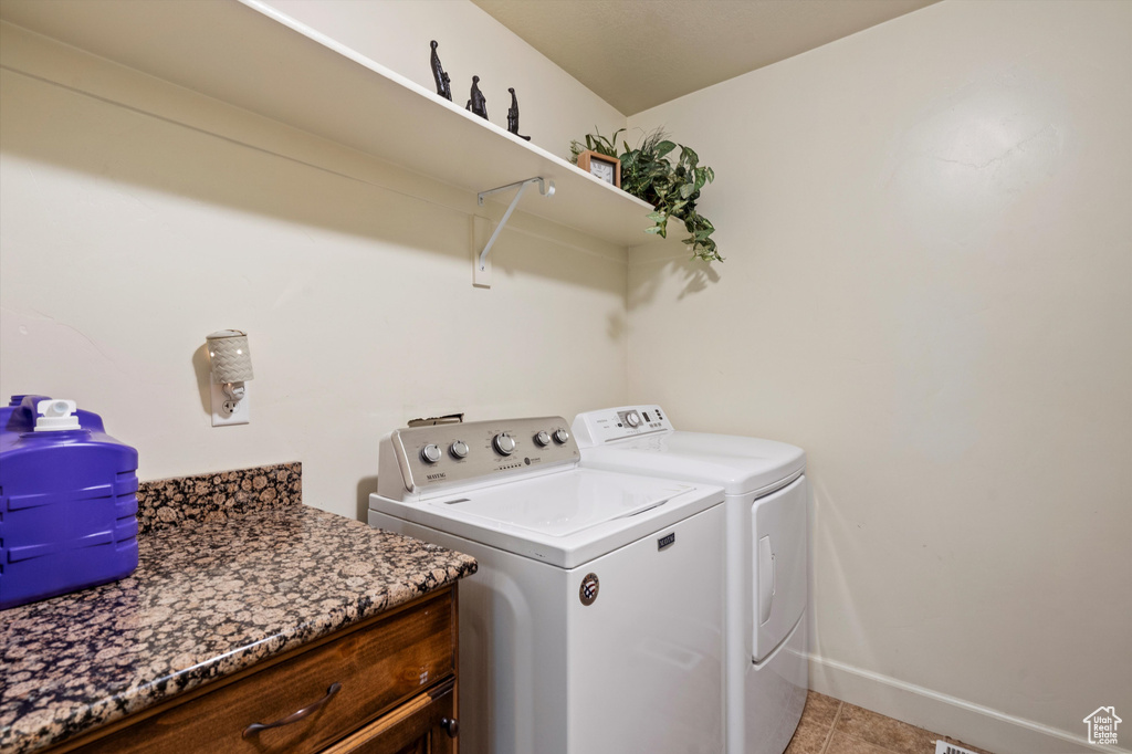 Clothes washing area featuring washing machine and dryer and light tile patterned floors