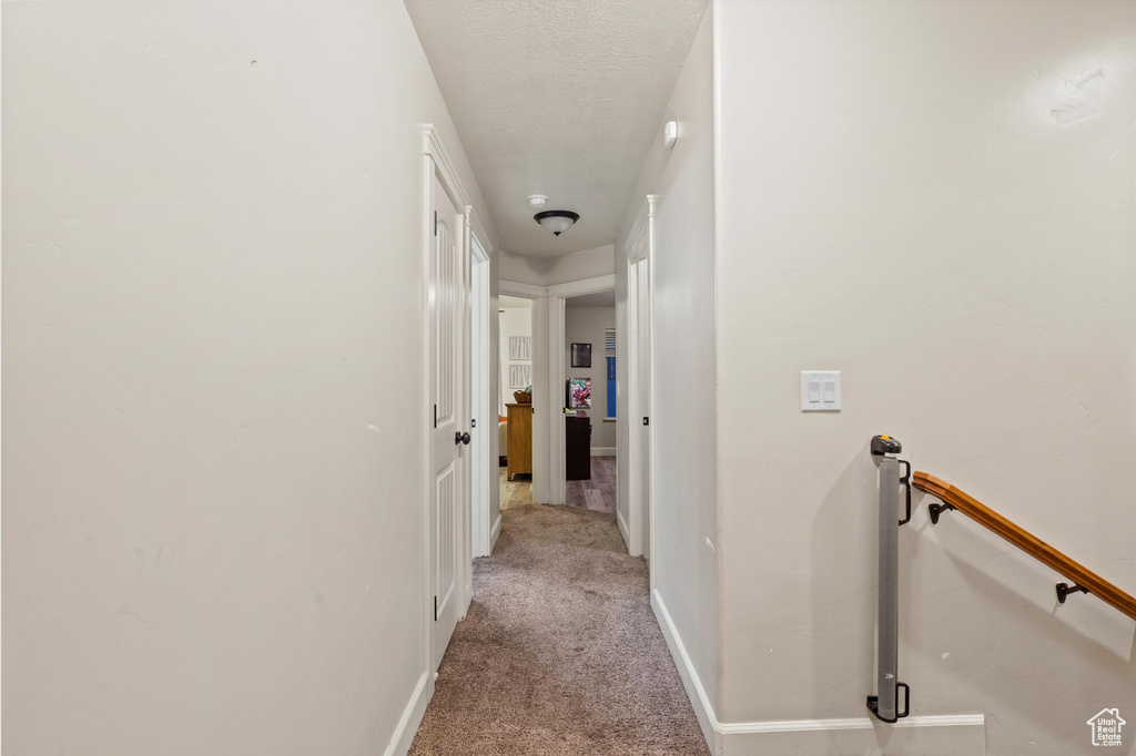 Corridor with light carpet and a textured ceiling