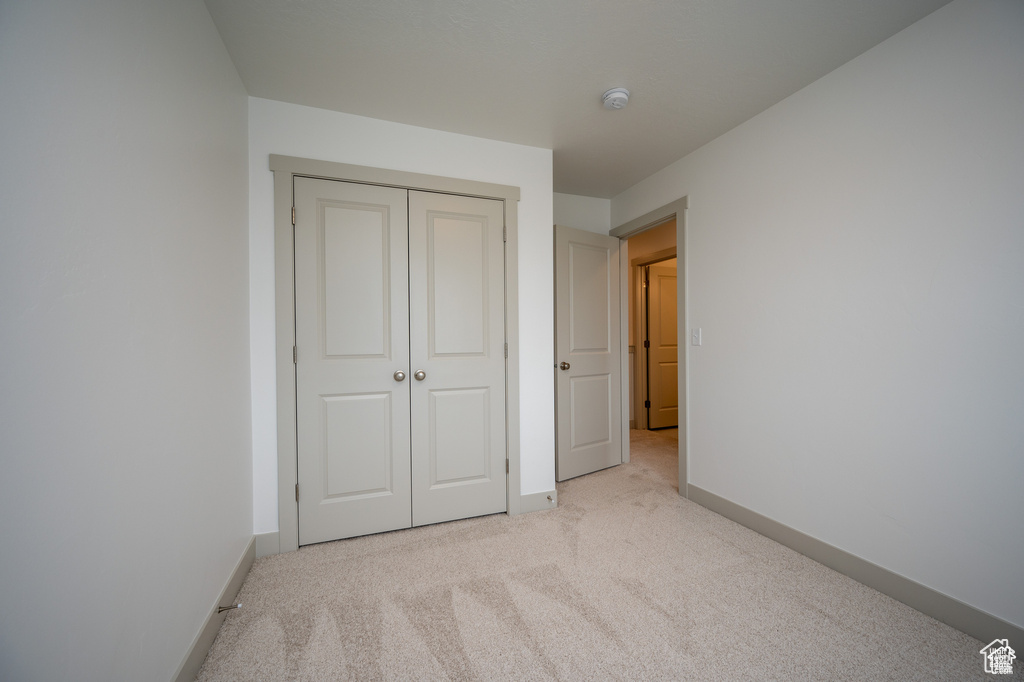 Unfurnished bedroom featuring light carpet and a closet