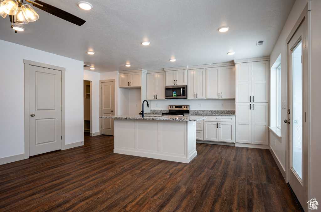 Kitchen featuring white cabinets, a kitchen island with sink, dark wood-type flooring, sink, and stainless steel appliances