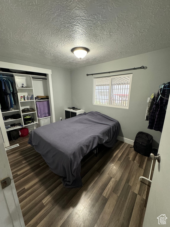 Bedroom with a textured ceiling and dark hardwood / wood-style floors