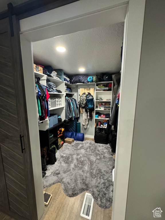 Walk in closet featuring a barn door and hardwood / wood-style flooring