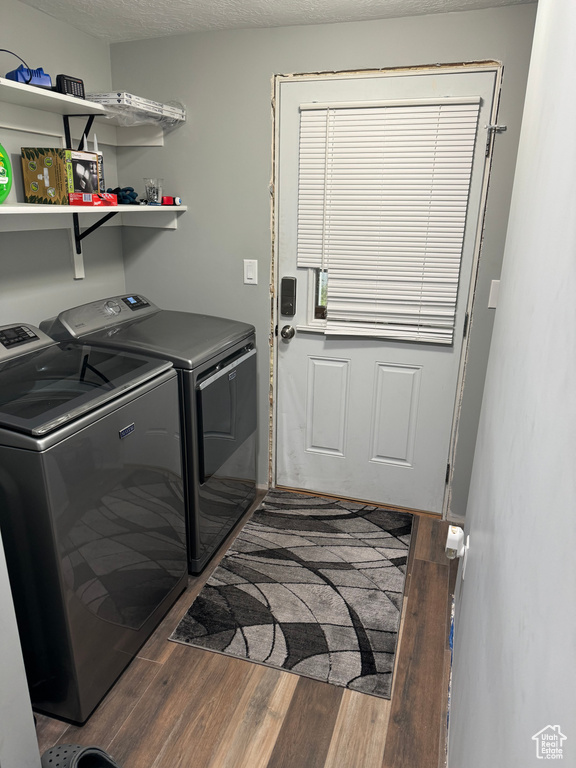 Clothes washing area featuring hardwood / wood-style floors, a textured ceiling, and washer and clothes dryer