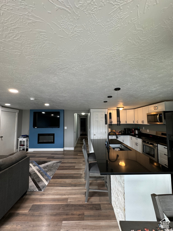 Interior space featuring sink, pendant lighting, appliances with stainless steel finishes, a textured ceiling, and dark hardwood / wood-style flooring