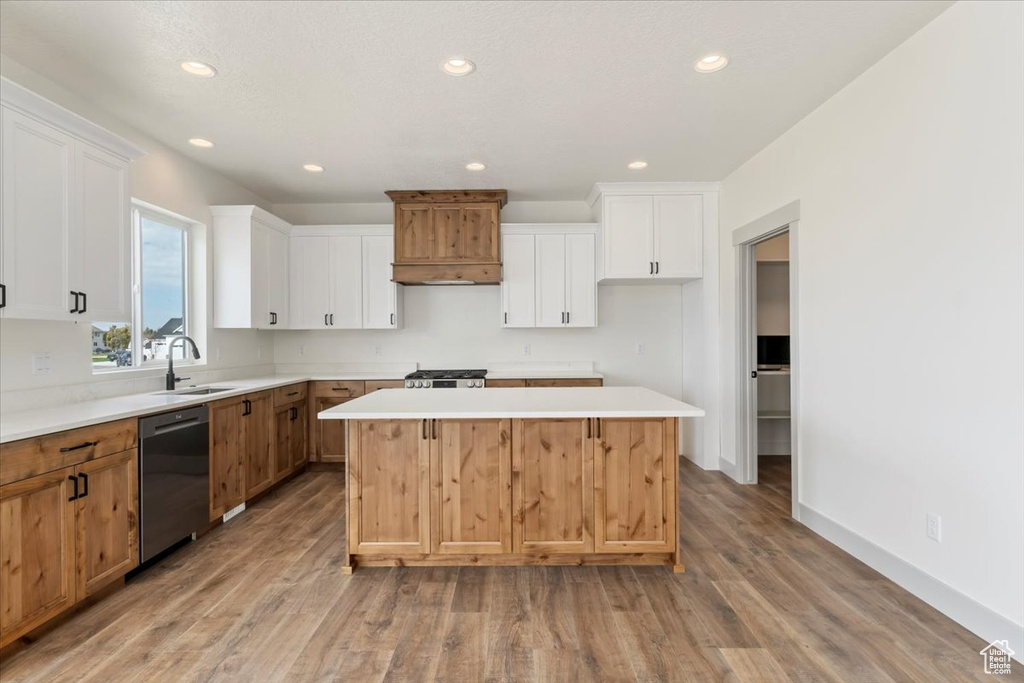 Kitchen with white cabinets, a kitchen island, light hardwood / wood-style flooring, sink, and stainless steel appliances