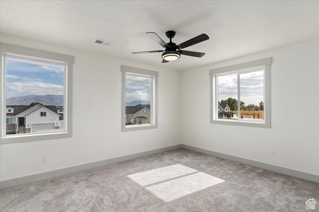 Empty room featuring a textured ceiling, light colored carpet, and ceiling fan