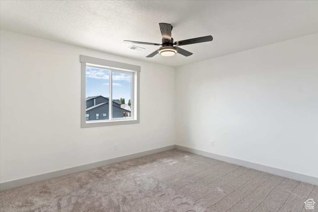 Spare room with ceiling fan, a textured ceiling, and light colored carpet