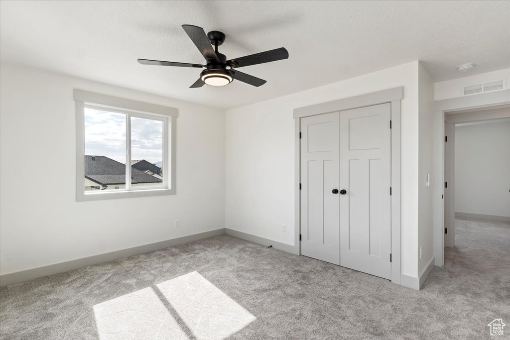 Unfurnished bedroom with a closet, ceiling fan, and light carpet