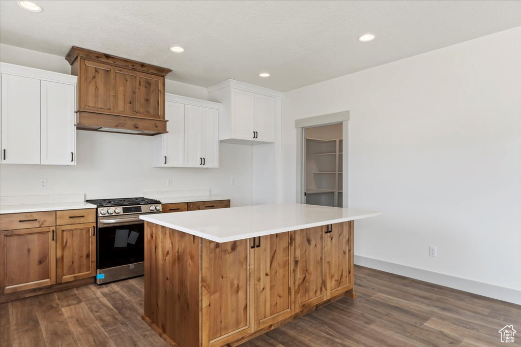 Kitchen with stainless steel gas range, a kitchen island, white cabinetry, and dark hardwood / wood-style floors