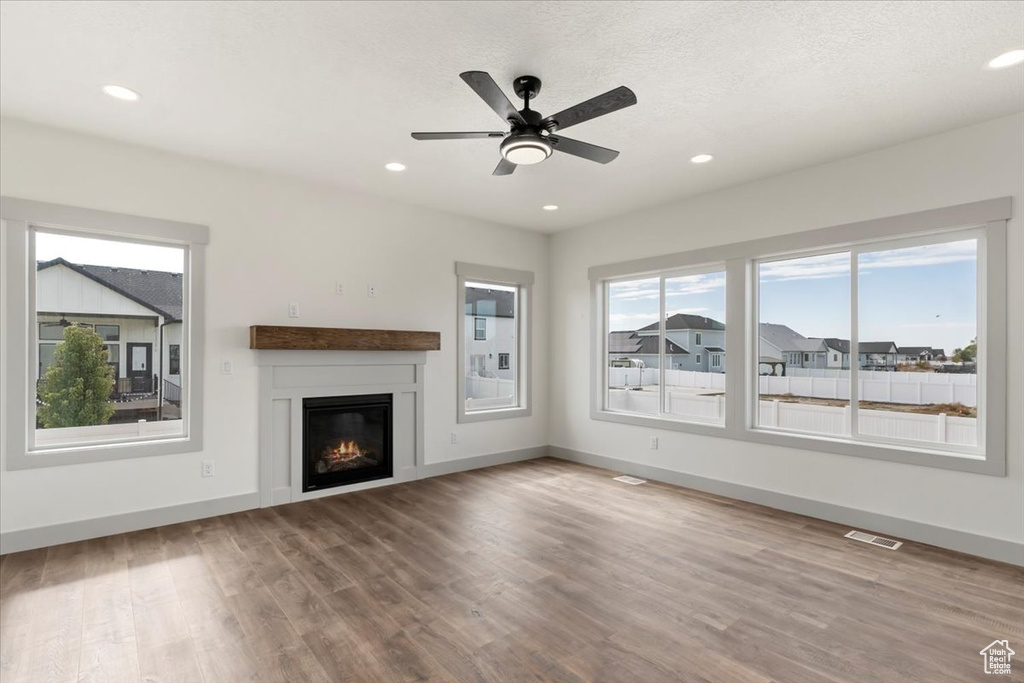 Unfurnished living room featuring ceiling fan, a textured ceiling, and hardwood / wood-style floors