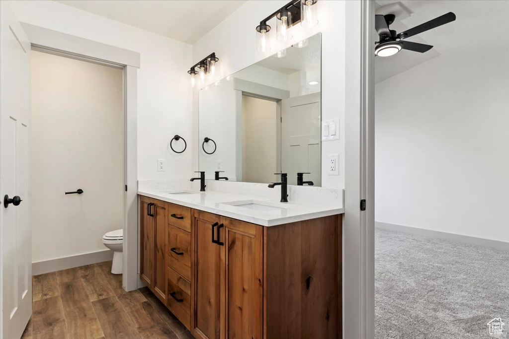 Bathroom featuring vanity, hardwood / wood-style floors, toilet, and ceiling fan