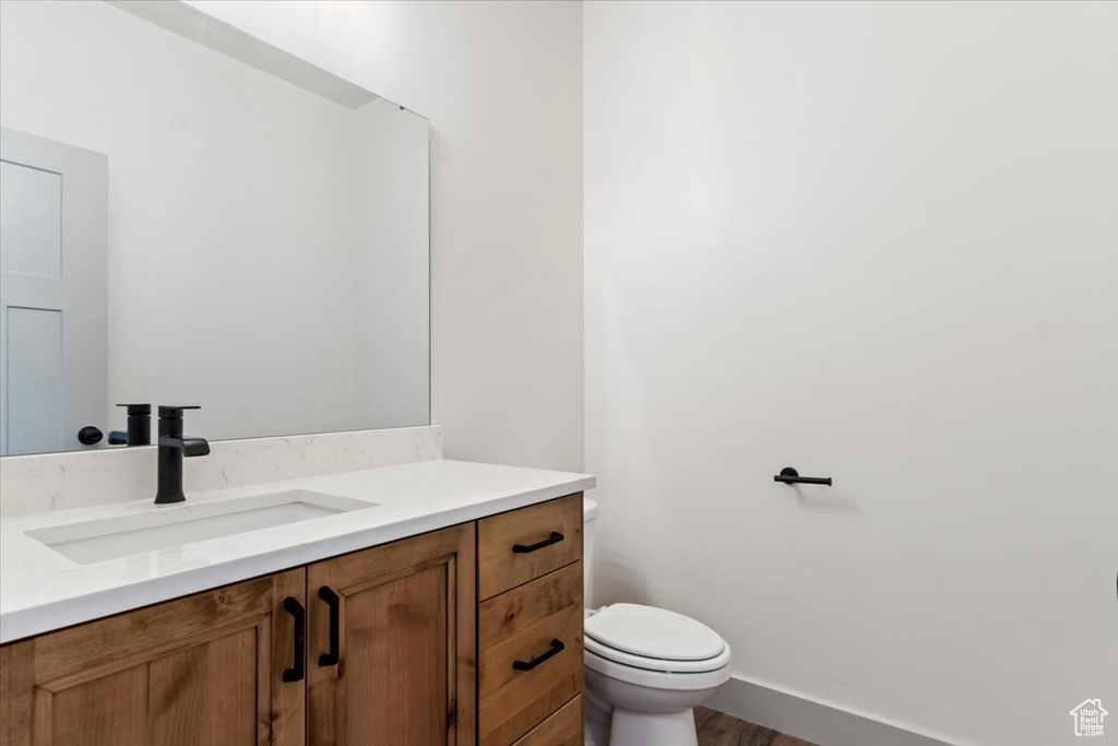 Bathroom featuring vanity, hardwood / wood-style floors, and toilet