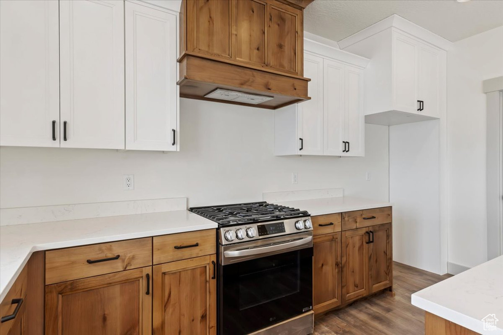 Kitchen featuring white cabinets, gas stove, and wood-type flooring